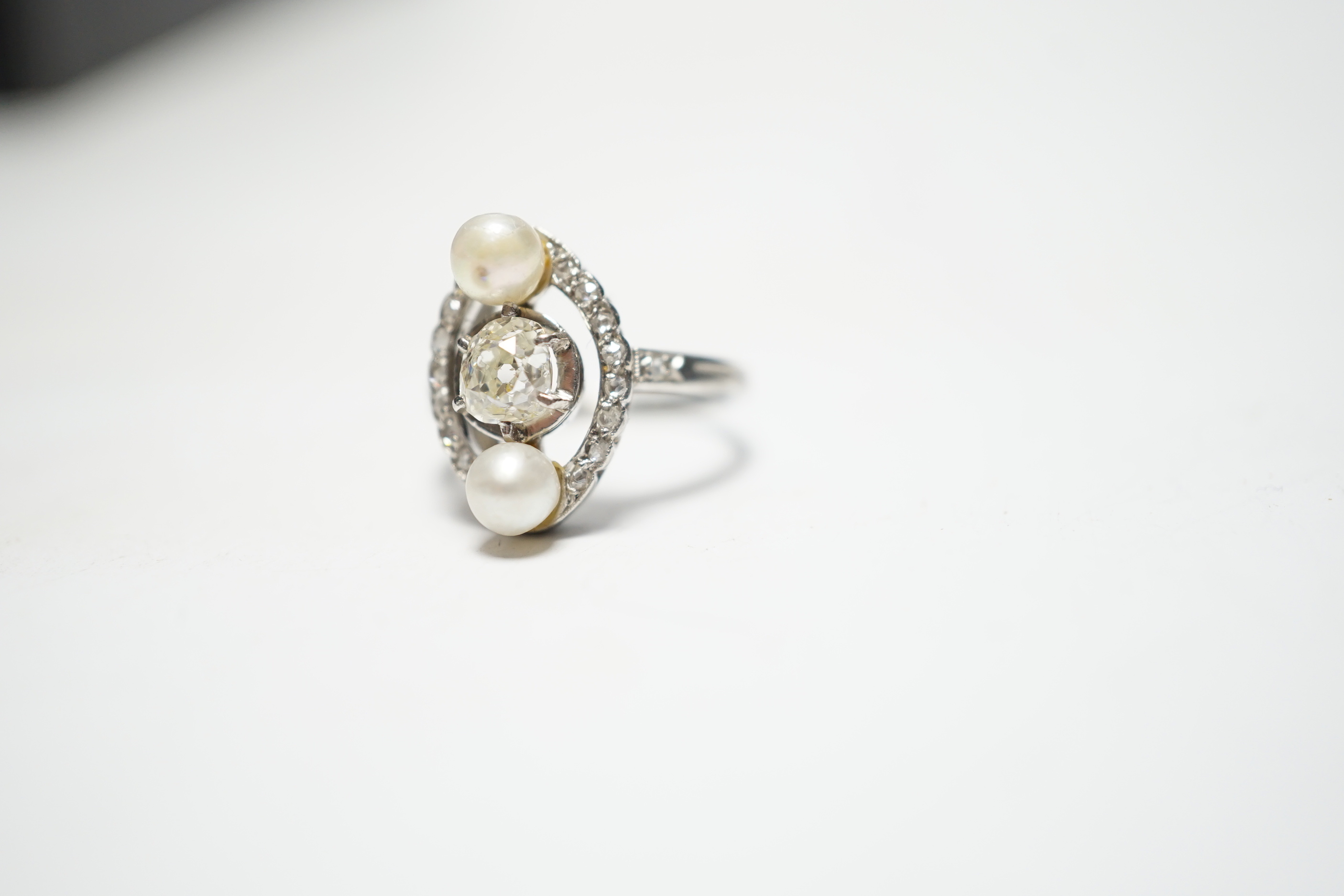 A white metal single stone diamond and two stone cultured pearl set oval ring, with diamond chip set borders and shoulders, size F, gross weight 4.4 grams.
